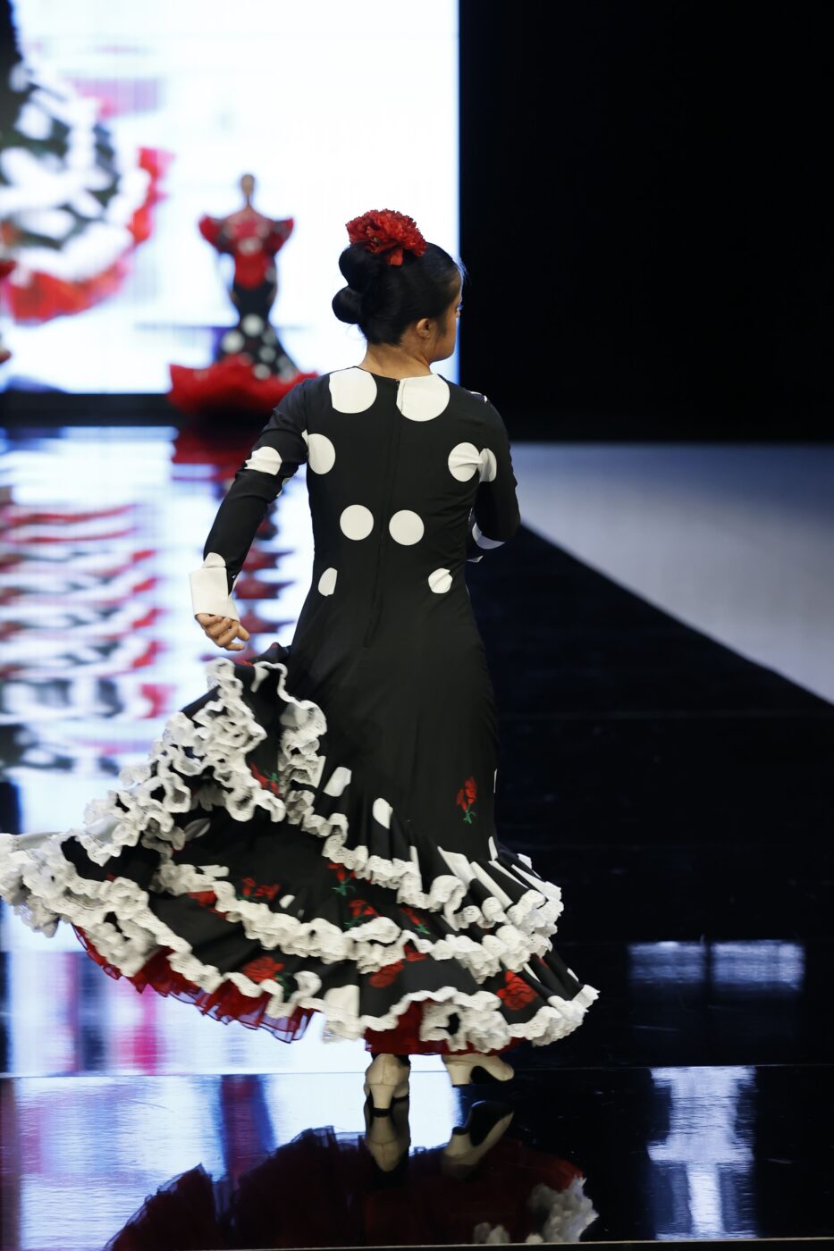 Traje de flamenca negro con lunares blancos y claveles rojos